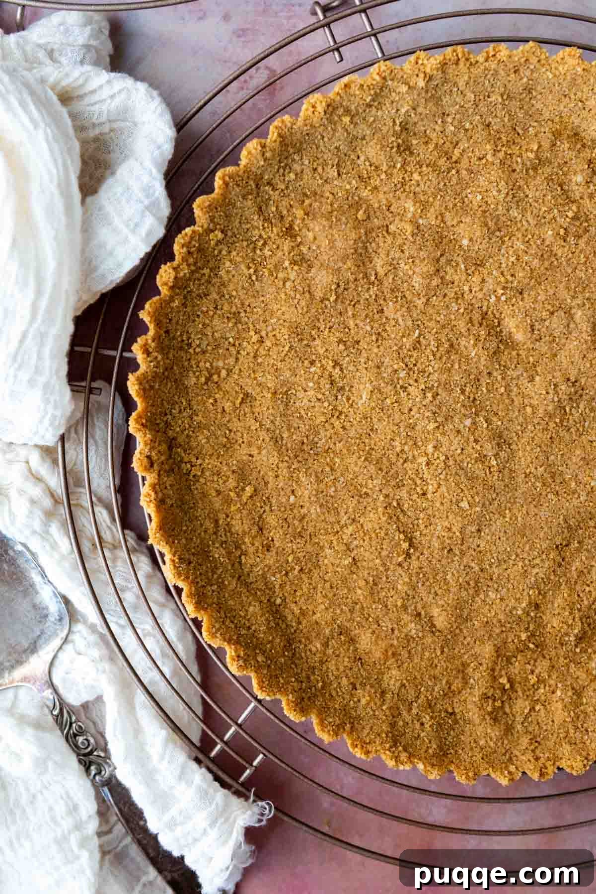 Quick Gluten Free Graham Cracker Crust Ready in 15 Minutes 2 graham cracker crust on a cooling rack with a towel next to it.