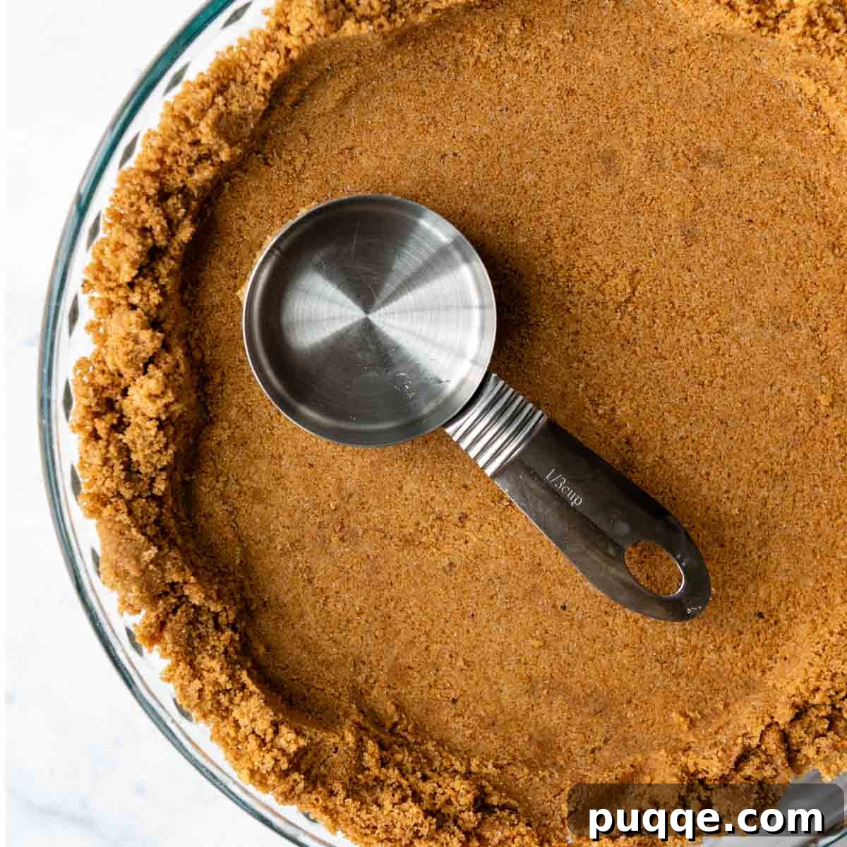Quick Gluten Free Graham Cracker Crust Ready in 15 Minutes 9 a measuring cup pressing down the bottom in a pie plate.