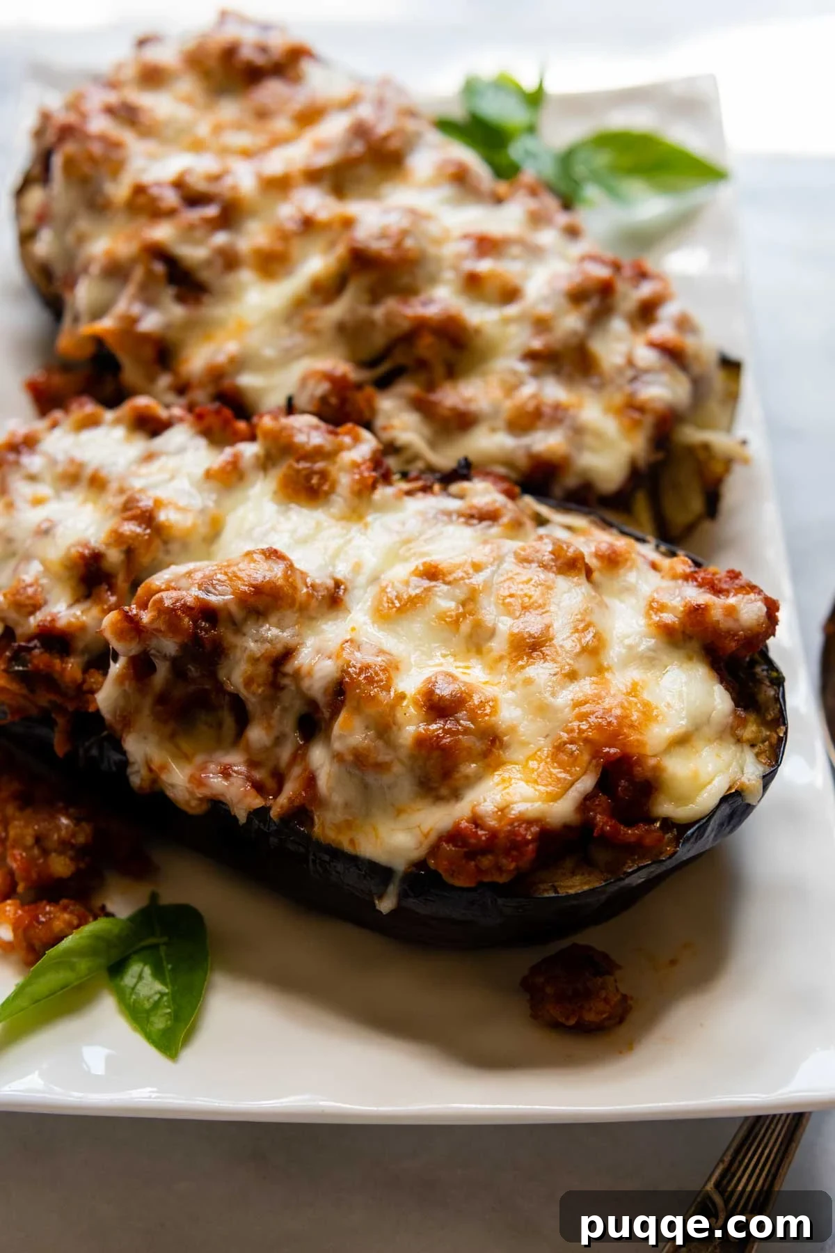 Hearty Gluten-Free Sausage-Filled Eggplant Boats 2 close up of baked eggplant on a white dish.