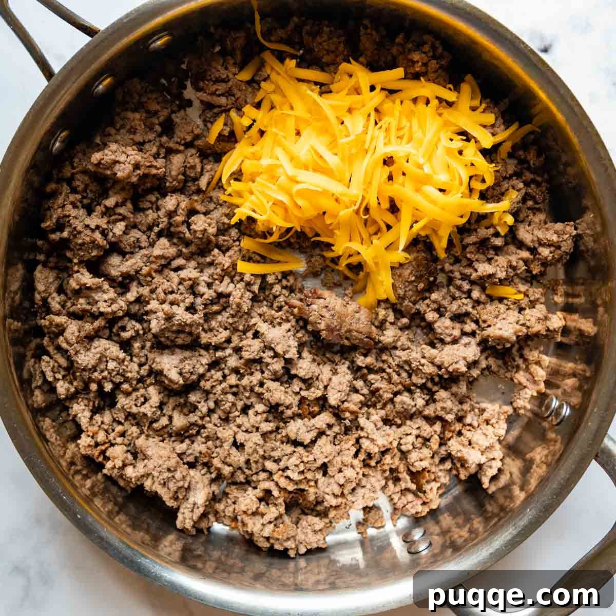 Gooey Cheeseburger Bowls with Crispy Bacon and Mystery Sauce 5 Seasoned ground beef browning in a skillet, with cheddar cheese being stirred in, creating a rich, cheesy burger mixture for the bowls.