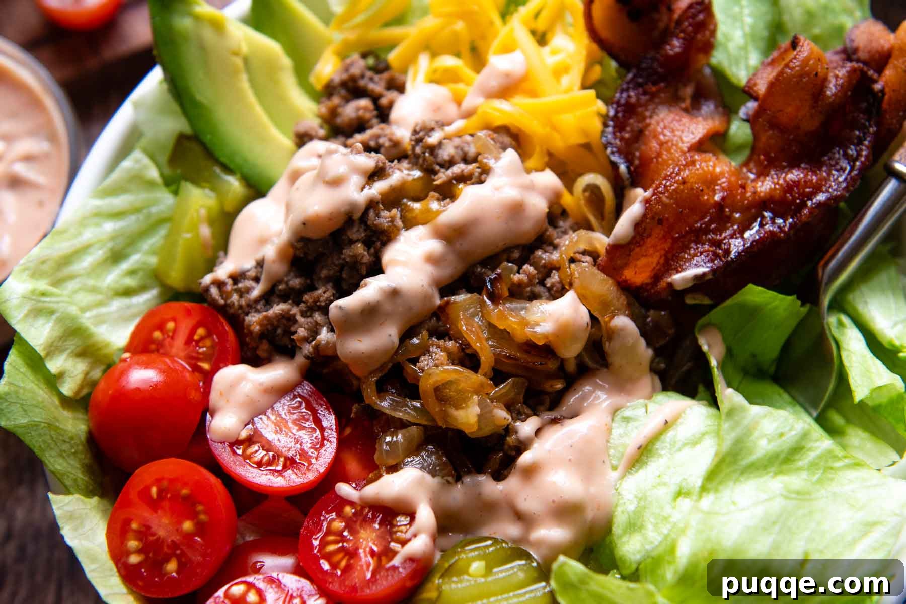 Gooey Cheeseburger Bowls with Crispy Bacon and Mystery Sauce 7 A close-up shot of the savory ground beef and melted cheese mixture nestled on a bed of fresh lettuce within a white salad bowl, demonstrating the inviting textures of the burger bowl.