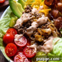 a burger bowl in a white bowl with sauce drizzled on top.