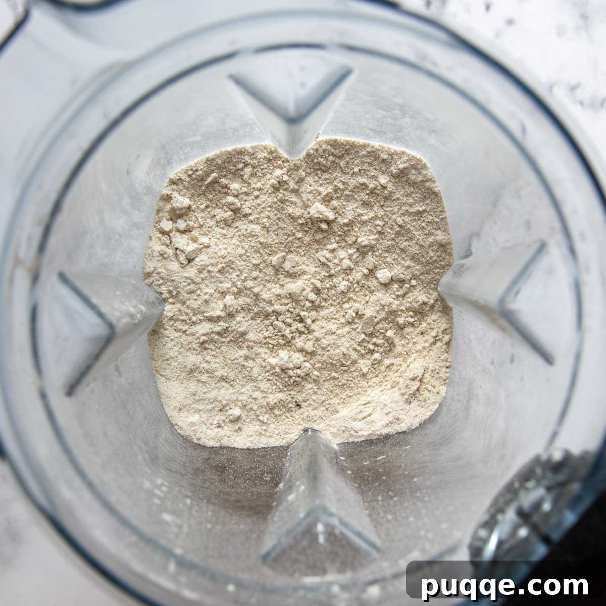 Rolled oats being poured into a high-powered blender, ready to be processed into oat flour.