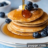Syrup being poured on a stack of oat flour pancakes.