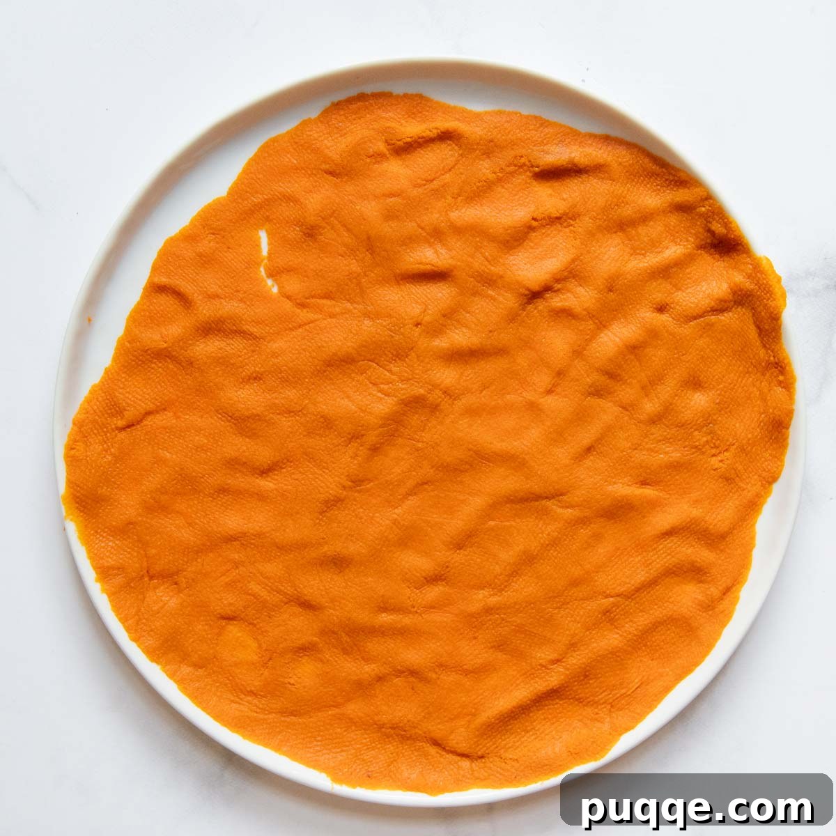 The Ultimate Chewy Gluten-Free Pumpkin Cookies 3 Canned pumpkin puree spread thinly on a white plate, ready for moisture removal with a paper towel.