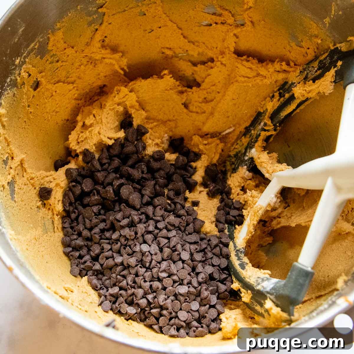 The Ultimate Chewy Gluten-Free Pumpkin Cookies 5 Semi-sweet and miniature chocolate chips being folded into the freshly mixed gluten-free pumpkin cookie dough, ensuring even distribution.