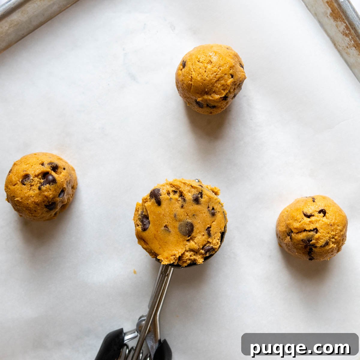 The Ultimate Chewy Gluten-Free Pumpkin Cookies 6 A large cookie scoop portions out gluten-free pumpkin cookie dough onto a parchment-lined baking sheet before chilling and baking.