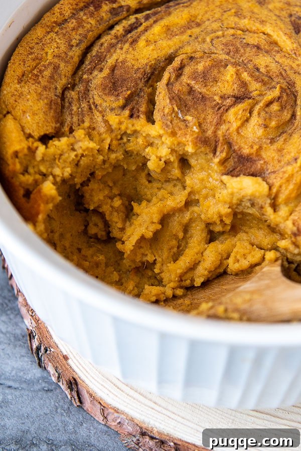 Simple Sweet Potato Spoon Bread Delight 5 A close-up of a scoop of golden-brown Southern sweet potato spoon bread taken out of a white casserole dish, showcasing its soft, moist texture.