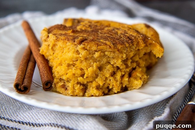 Simple Sweet Potato Spoon Bread Delight 6 A single serving of sweet potato spoon bread on a white plate with cinnamon sticks beside it, highlighting its rich, inviting color.