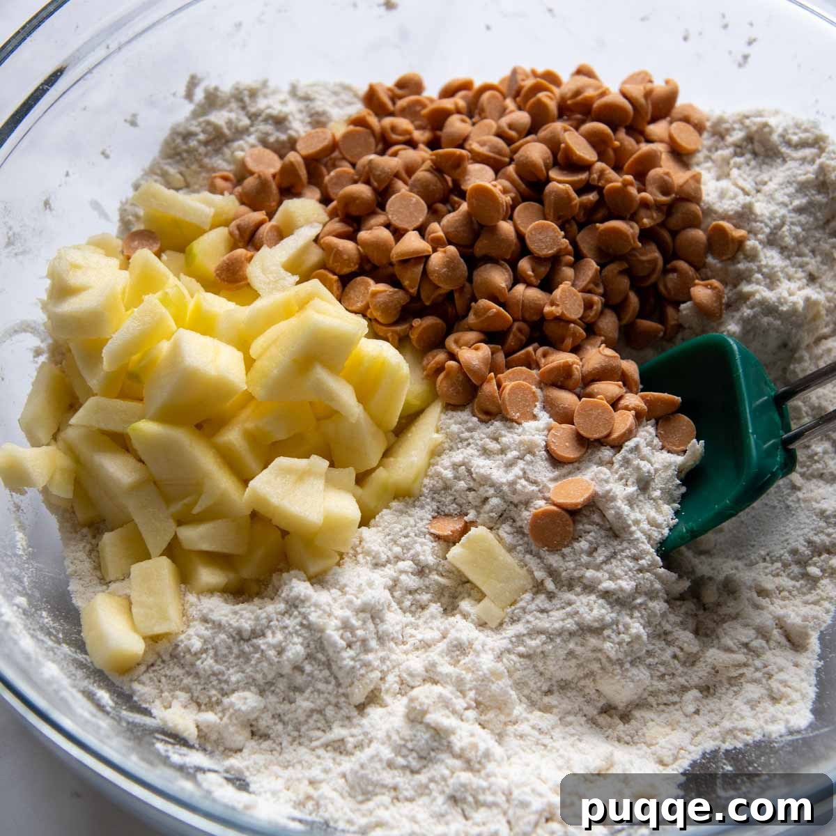 Diced apples and butterscotch chips being stirred into scone dough.