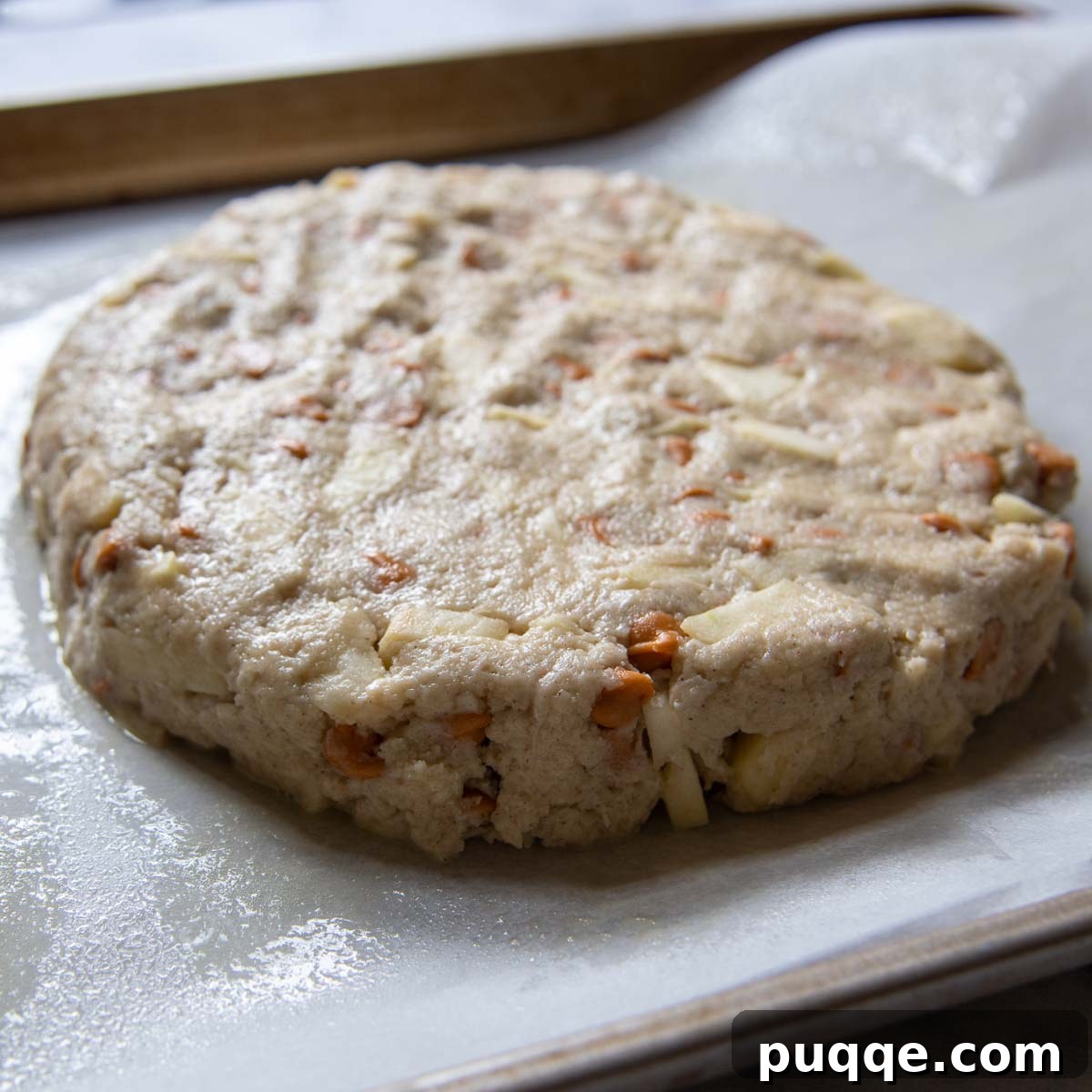 Round disc of scone dough pressed onto a baking sheet lined with parchment paper.