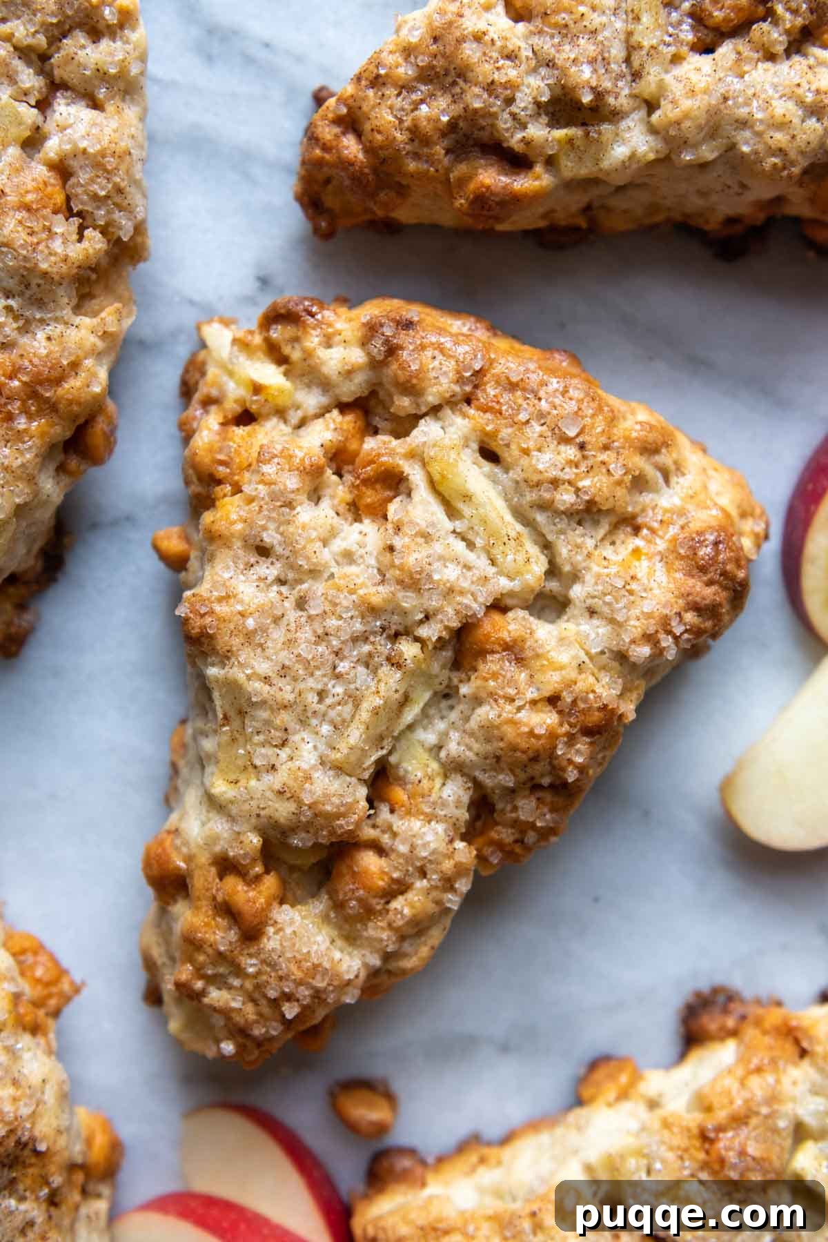 Overhead shot of freshly baked gluten-free apple scones with apple slices and cinnamon sticks scattered nearby.