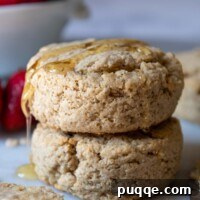 a stack of 2 biscuits with honey dripping over the top.
