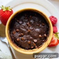 overhead shot of mug brownie in a yellow dish with berries next to it.
