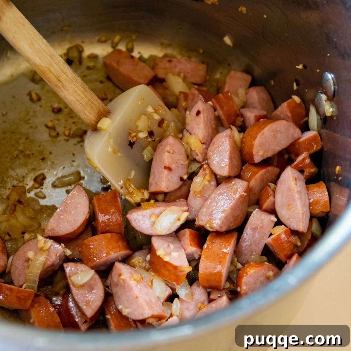 Sausage and onions sautéed in a pot.
