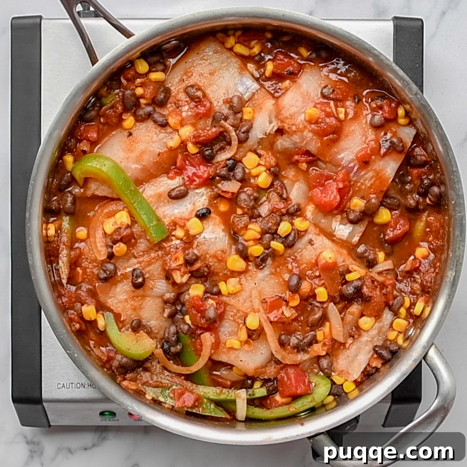 Quick Skillet Mexican Fish Dinner 6 White fish fillets simmering in a rich, red Mexican salsa sauce in a deep skillet.
