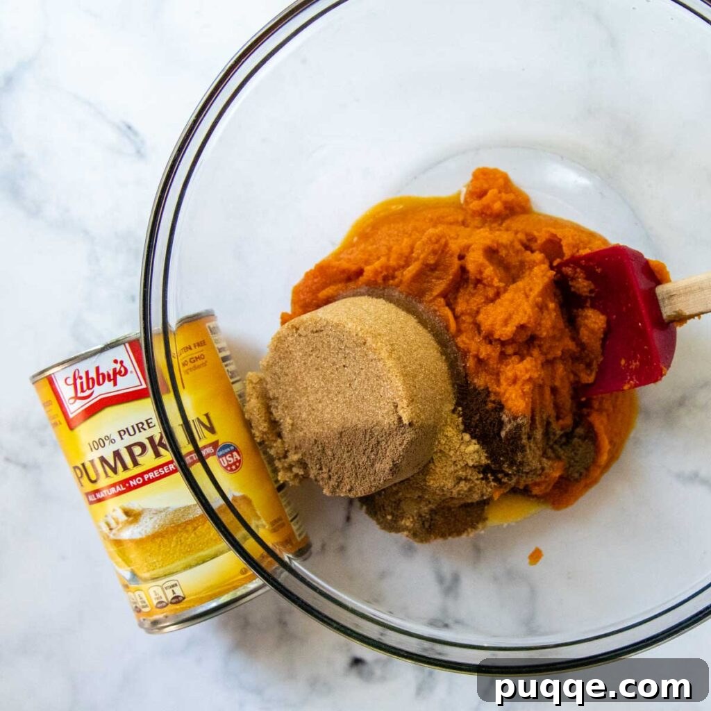 All the filling ingredients gathered in a bowl, with a can of pumpkin puree prominently displayed beside them.