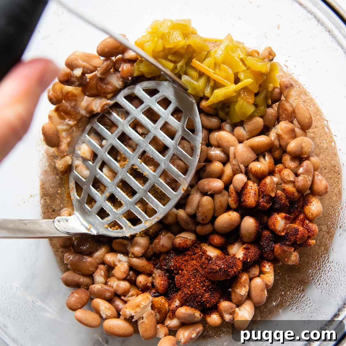 10-Minute Gluten-Free Cheesy Crunchwrap Quesadillas 3 a potato masher mashing beans with seasonings in a bowl.