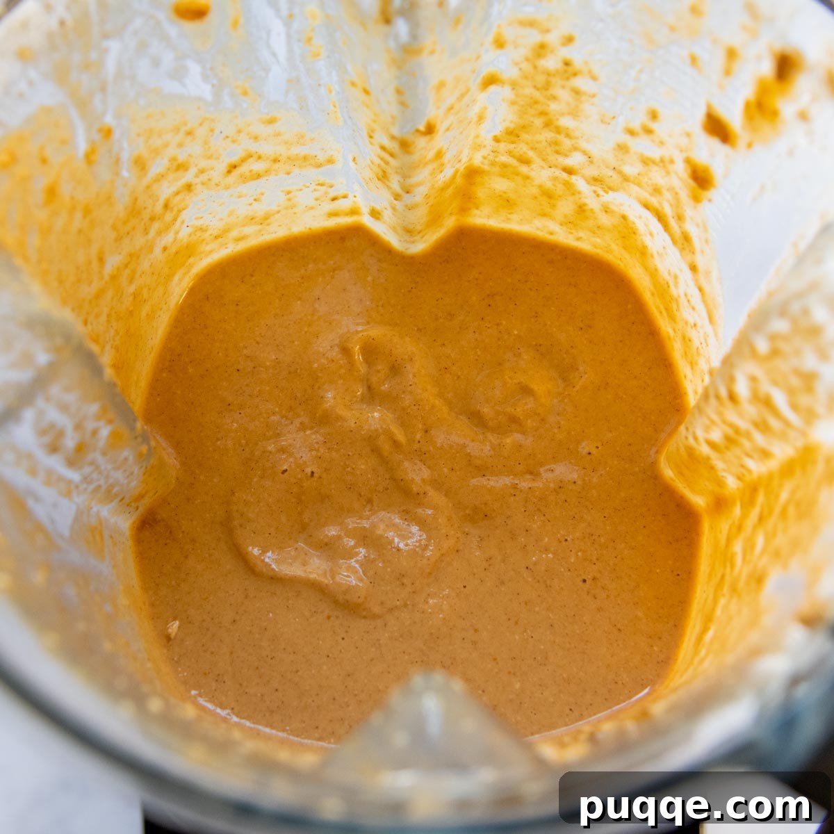Smooth pumpkin pancake batter in a blender after processing and resting, showcasing its thick consistency.