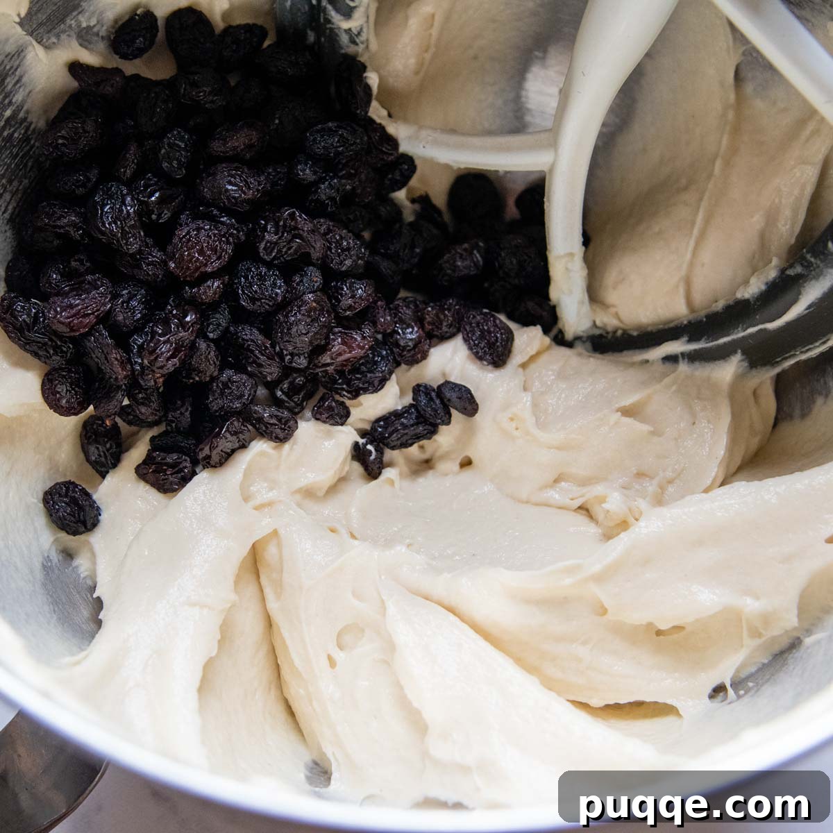 Bread dough with raisins in a large bowl, ready for mixing.