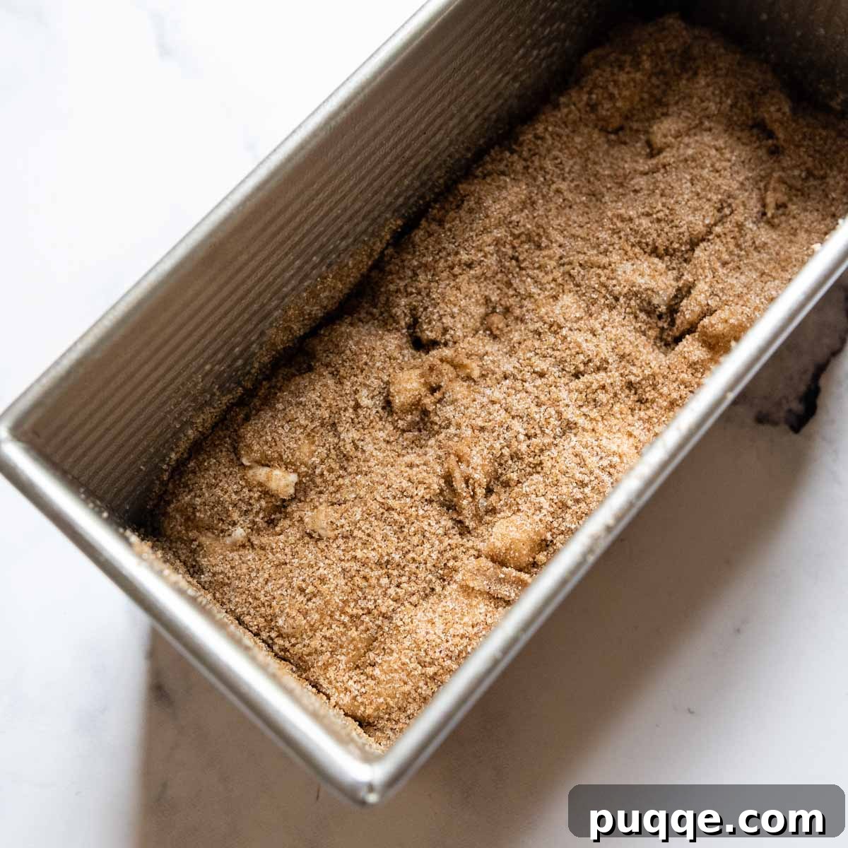 Cinnamon sugar mixture sprinkled on the first half of the dough in a loaf pan.