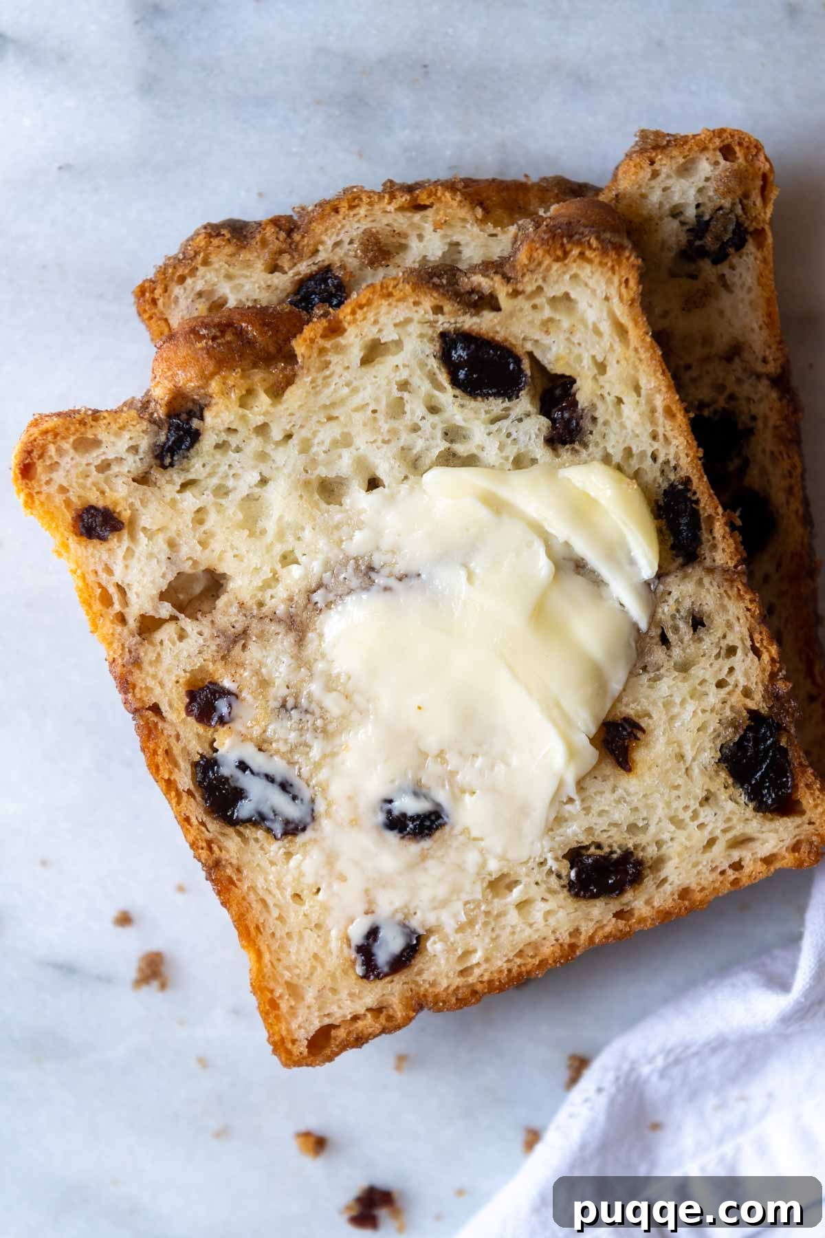 A slice of gluten-free cinnamon raisin bread with butter spread on top, ready to eat.