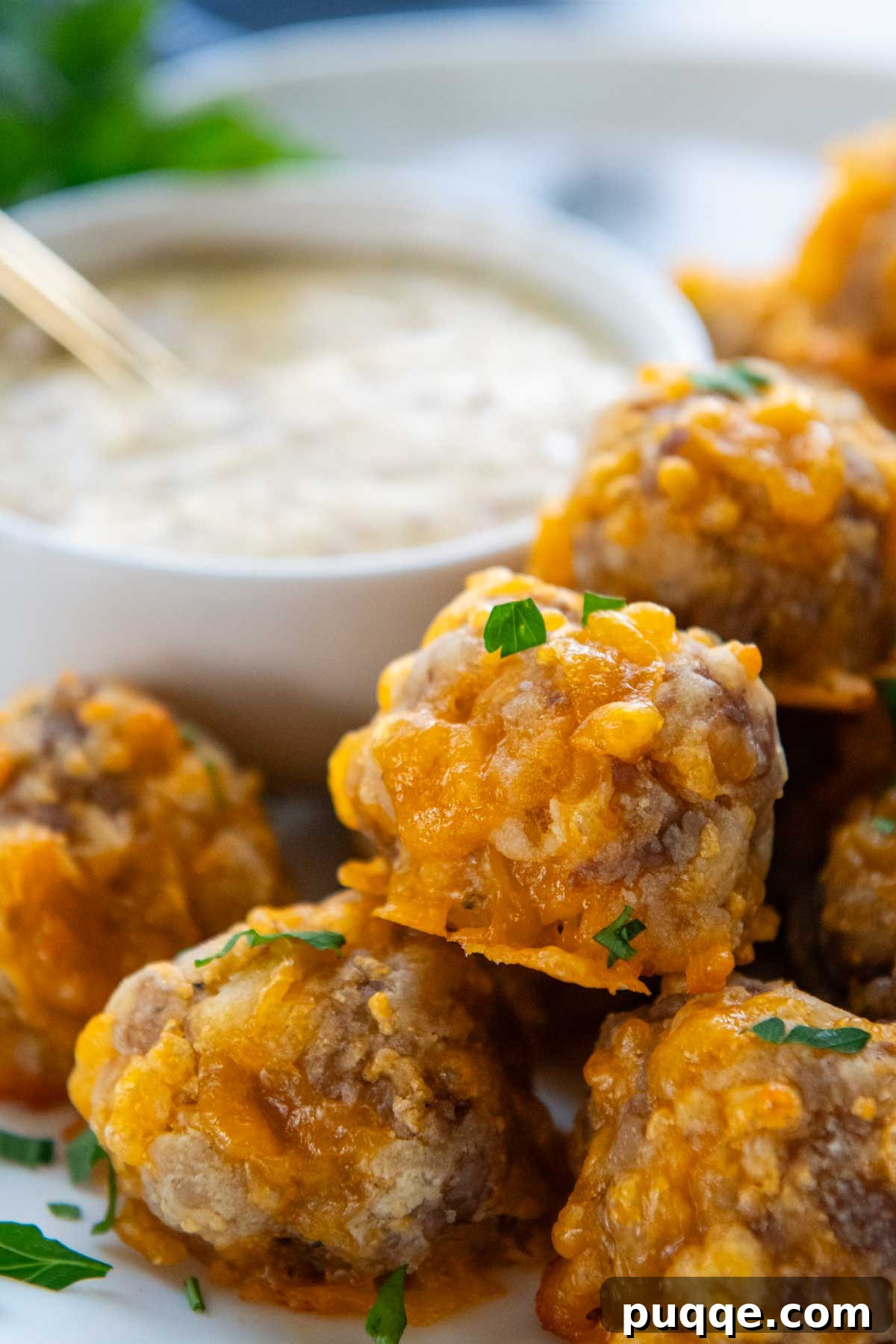 A close-up of golden, fluffy gluten-free sausage balls piled high on a white plate, ready to be served.