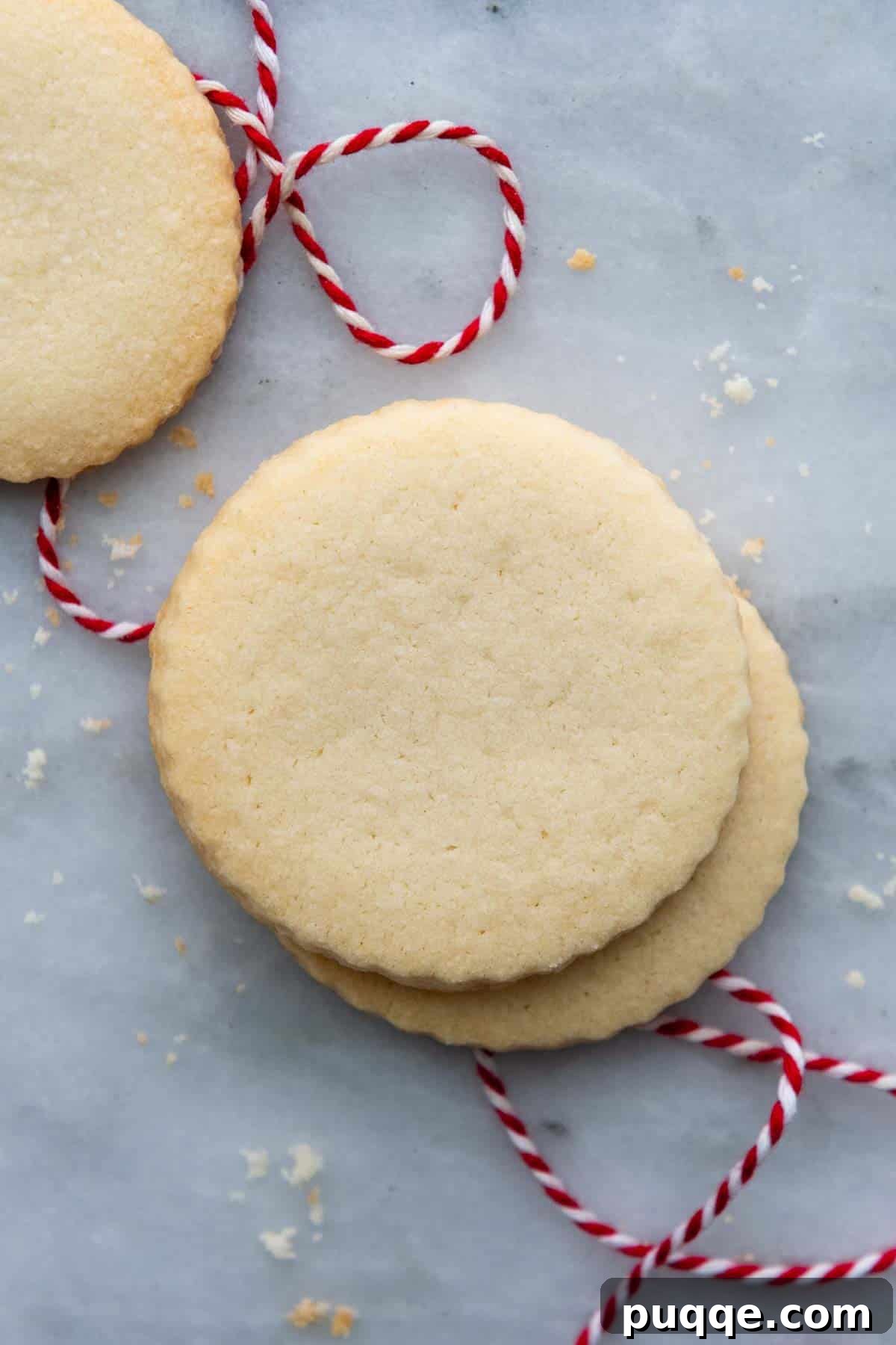 two shortbread cookies stacked with a red thread underneath.