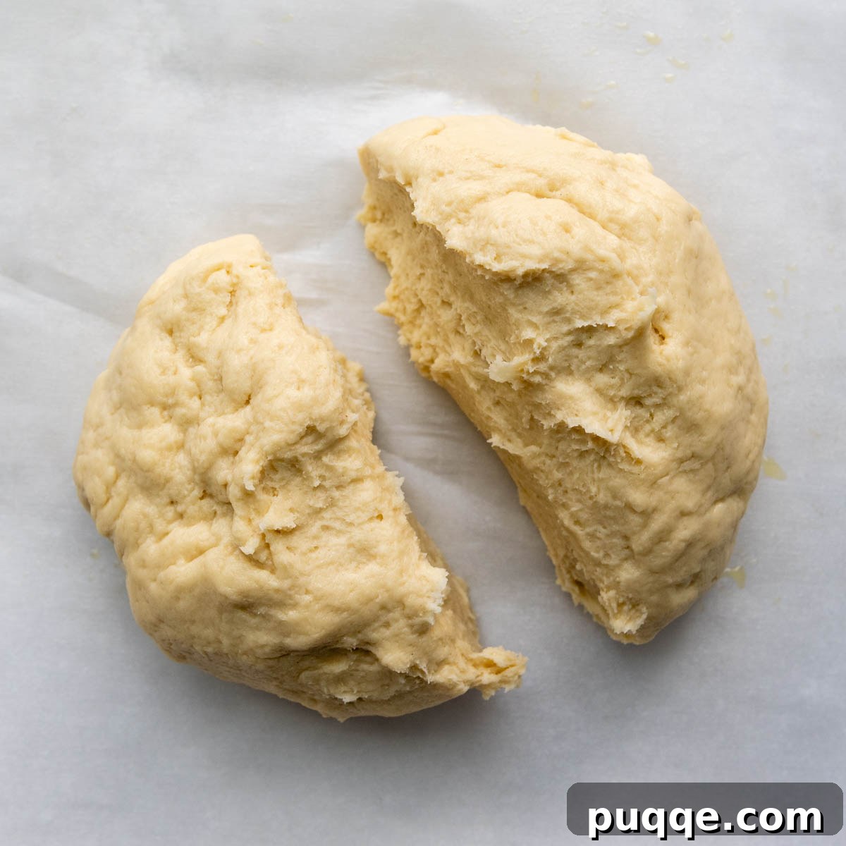 Gluten-free baguette dough precisely cut into two equal halves on parchment paper.