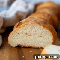A slice of perfect gluten-free French bread on a wooden cutting board.