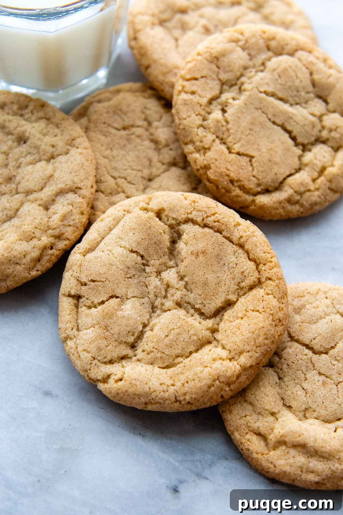 Freshly baked gluten-free snickerdoodles arranged artfully on a marble surface, with a glass of milk nearby, inviting a delightful treat.