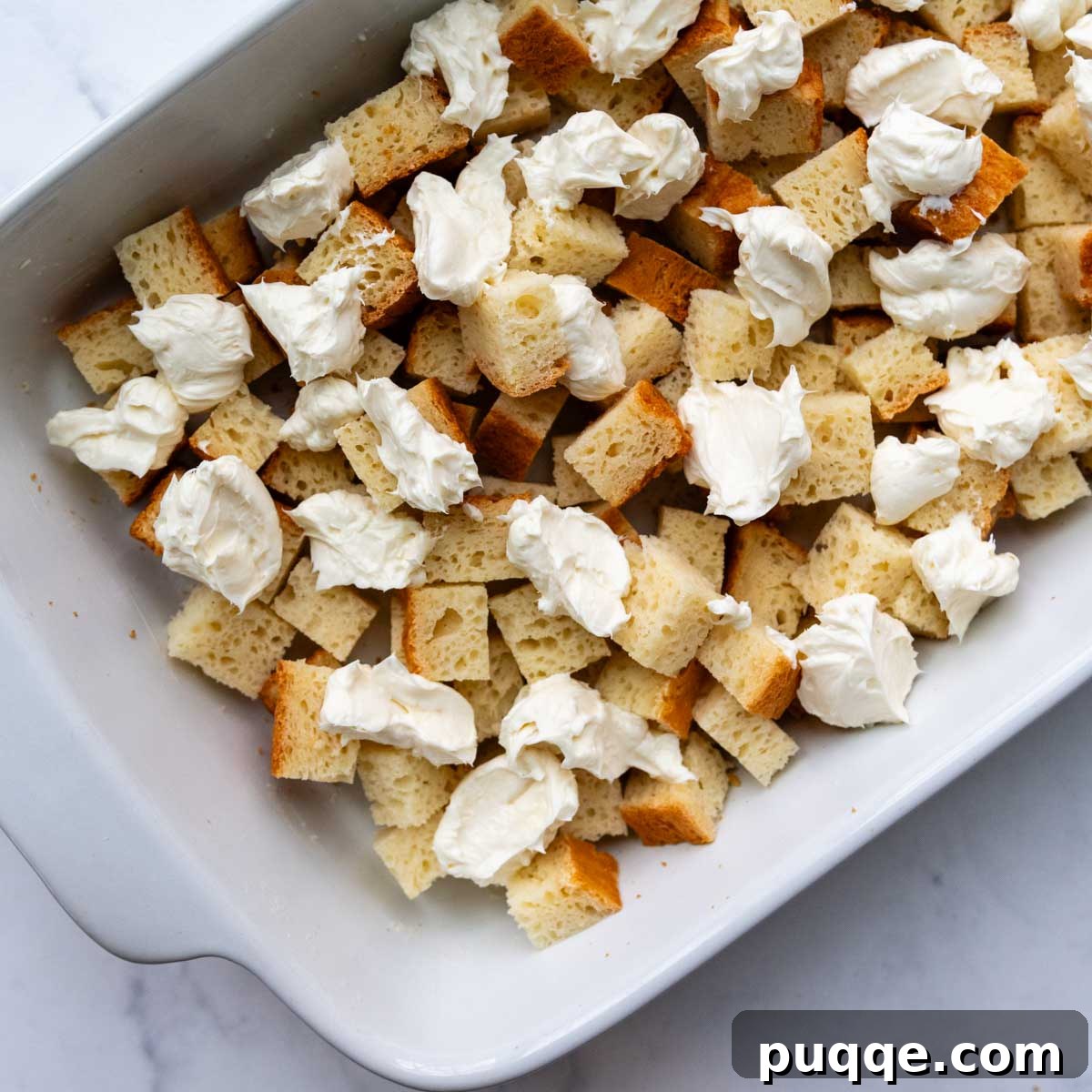 Perfect Overnight Gluten-Free French Toast Casserole 5 Half of the bread mixture with dollops of cream cheese on top in a baking dish.