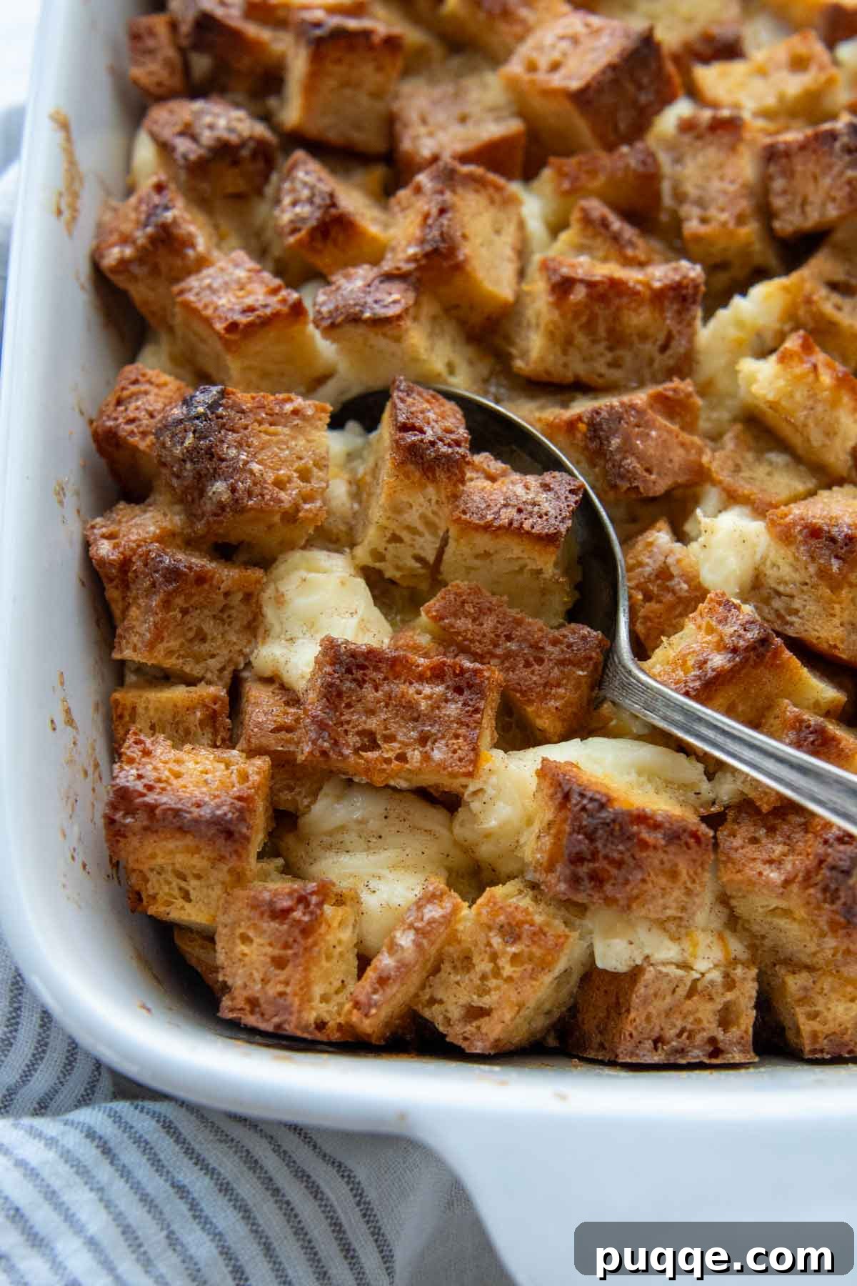 Perfect Overnight Gluten-Free French Toast Casserole 7 A spoon scooping into the top of a freshly baked gluten-free French toast casserole.