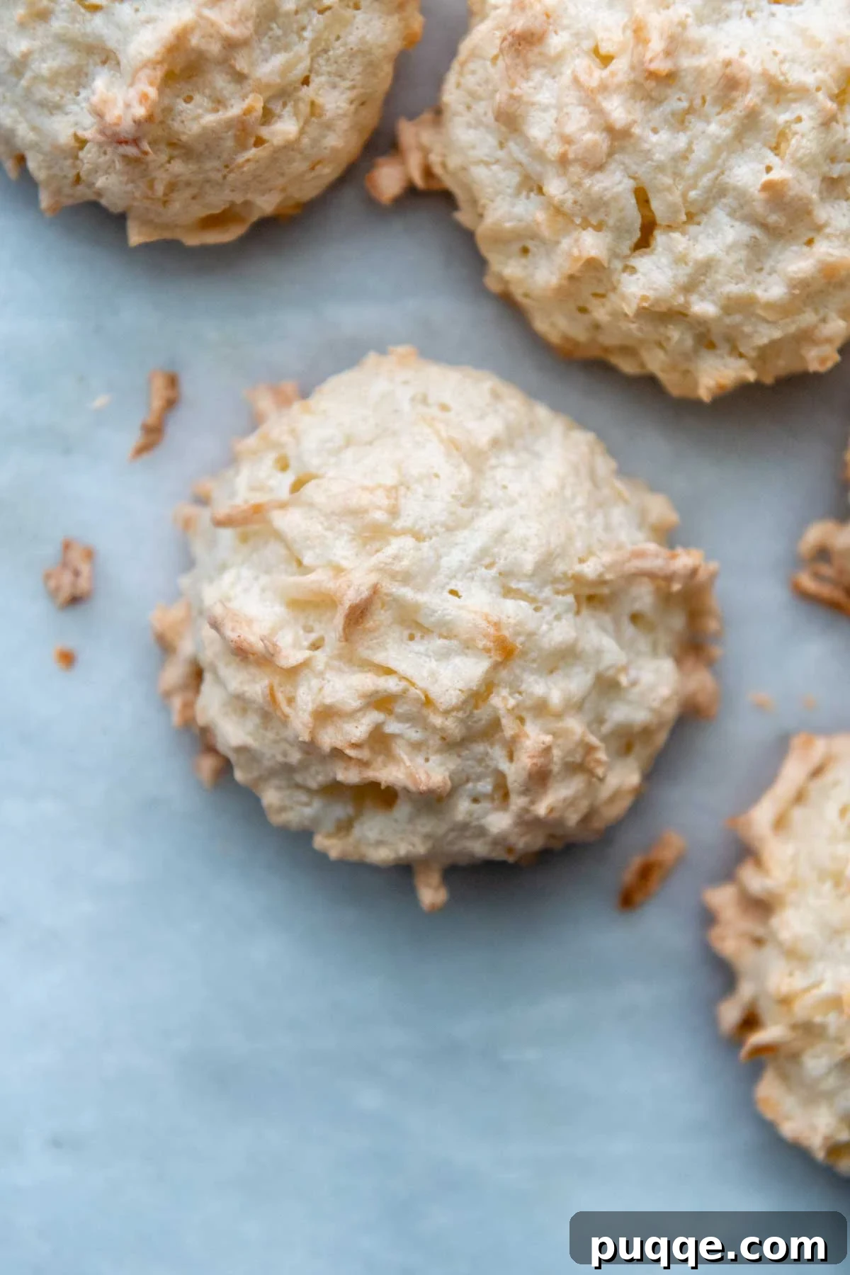 Featherlight Gluten-Free Coconut Delights 2 top view of perfectly baked golden brown gluten-free coconut macaroons on a white background.