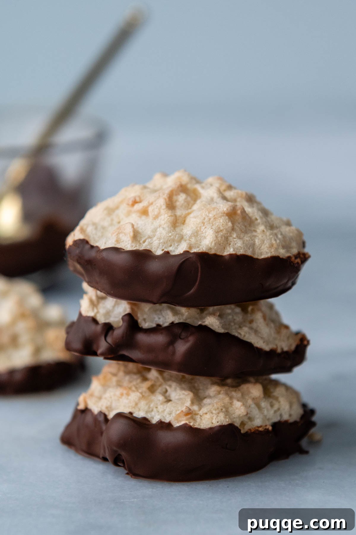 Featherlight Gluten-Free Coconut Delights 11 a stack of three coconut macaroons with their bottoms dipped in chocolate.