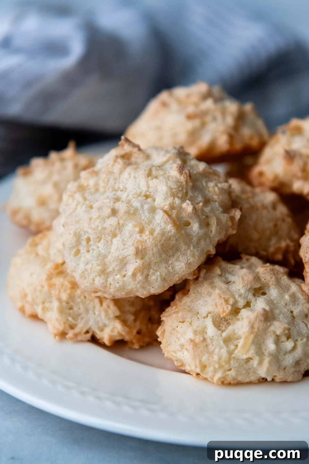 Featherlight Gluten-Free Coconut Delights 12 a beautiful pile of golden gluten-free coconut macaroons presented on a white plate.