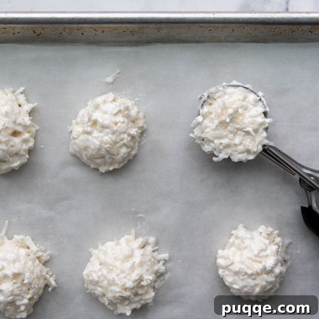 Featherlight Gluten-Free Coconut Delights 8 unbaked coconut macaroons perfectly scooped onto a parchment-lined baking sheet.