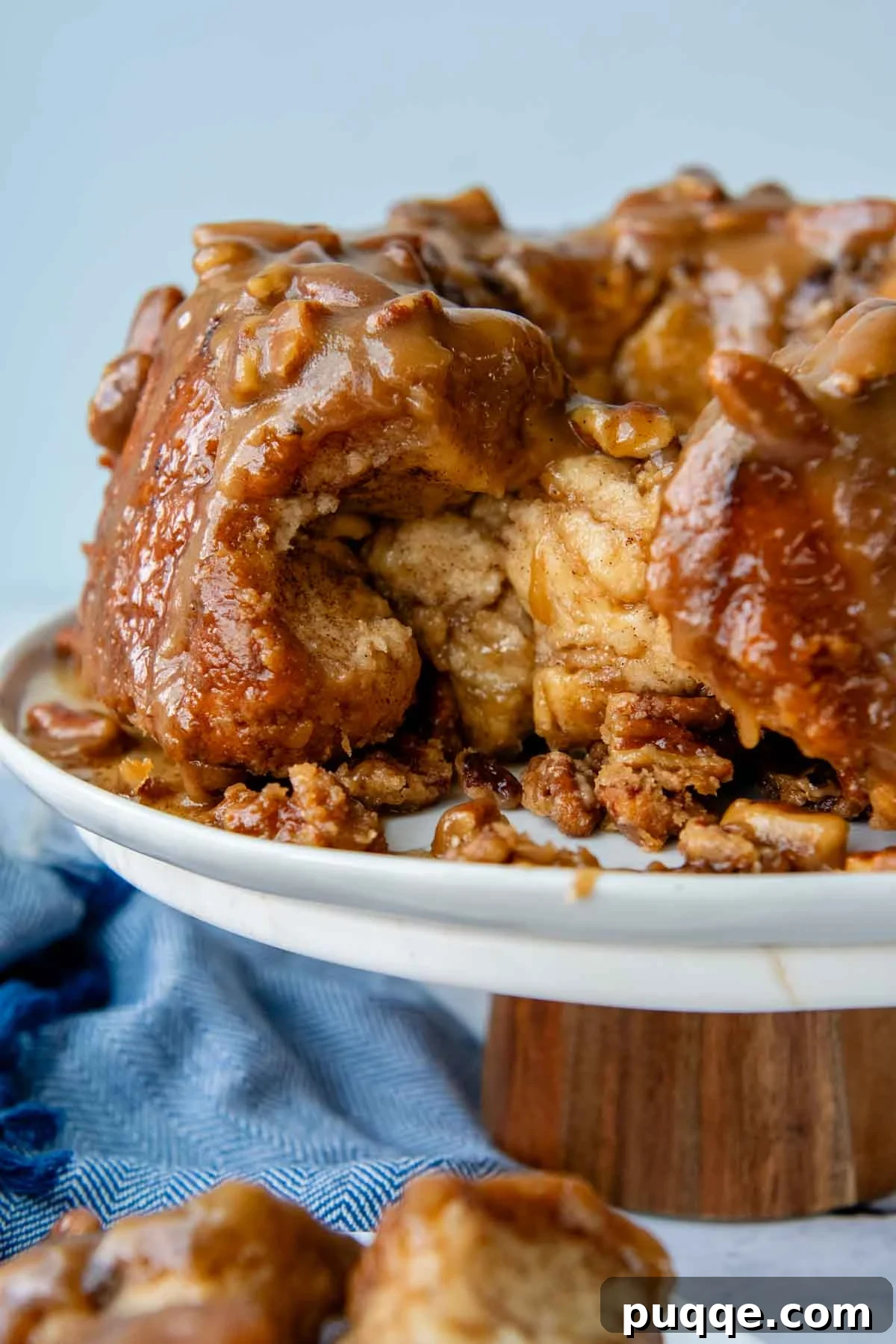 Melt-in-Your-Mouth Gluten Free Sticky Pull Apart Bread 2 A beautifully baked gluten-free monkey bread on a elegant cake platter with a portion pulled out, showcasing its gooey cinnamon layers.