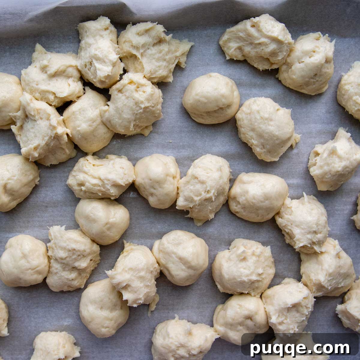 Melt-in-Your-Mouth Gluten Free Sticky Pull Apart Bread 5 Portioned gluten-free dough balls resting on greased parchment paper, ready for the next step.