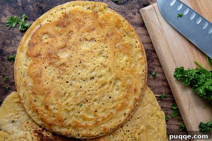 Your Go-To 5-Ingredient Socca Flatbread 9 an uncut farinata laying next to a cutting board with chopped parsley scattered around