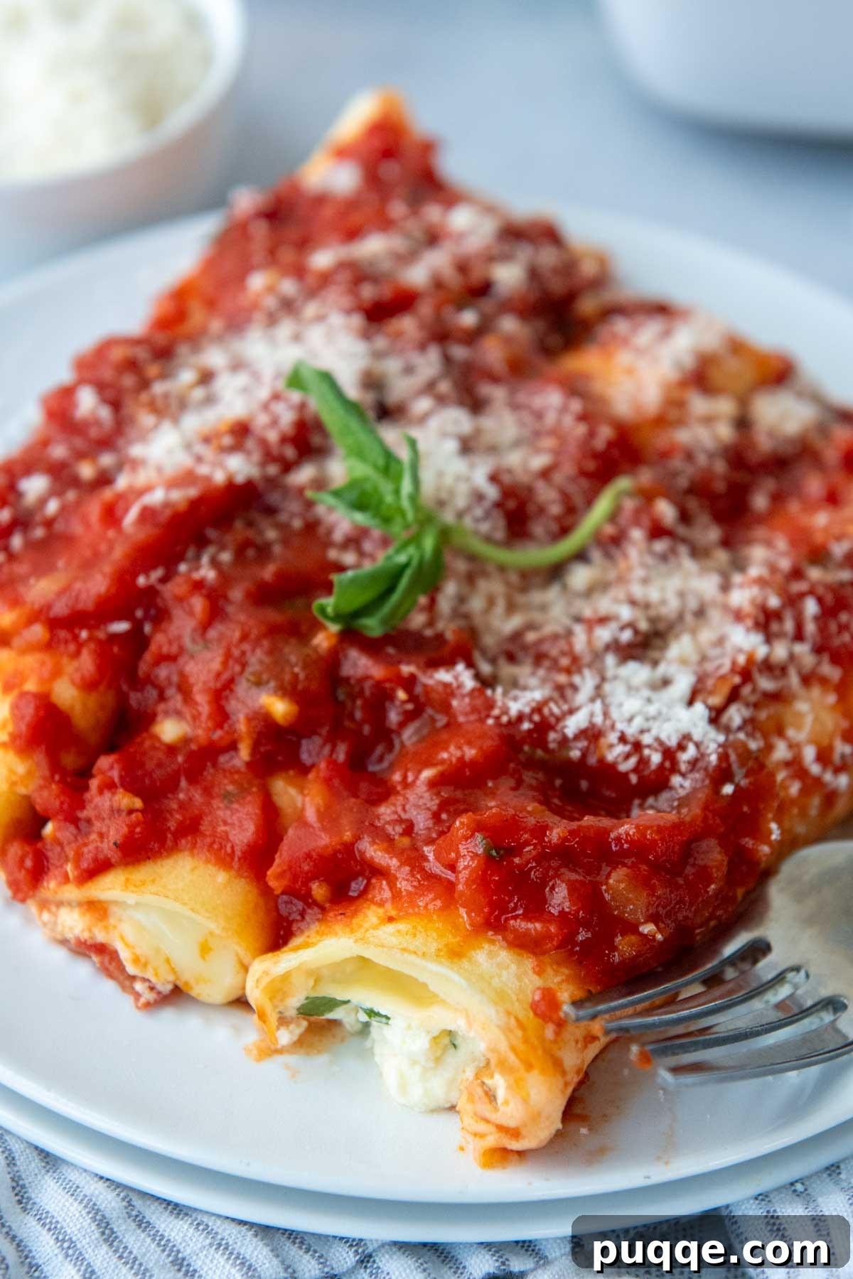 Effortless Homemade Gluten-Free Manicotti with Tender Crepe Shells 11 three perfectly baked manicotti shells with sauce over the top and fresh basil garnish.