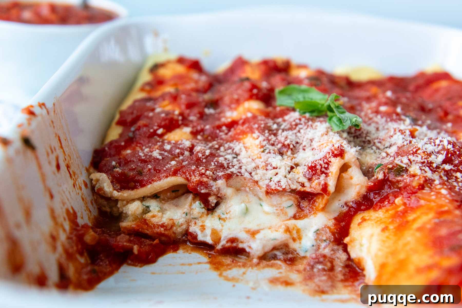 Effortless Homemade Gluten-Free Manicotti with Tender Crepe Shells 12 manicotti in a white baking dish with some taken out, ready to serve.
