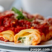 close up of the inside of manicotti on a white plate with fresh basil garnish.