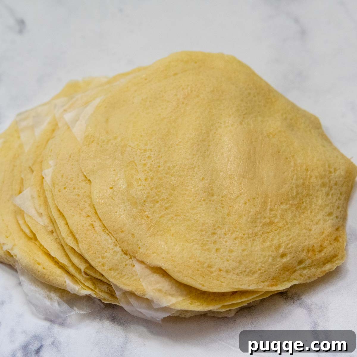 Effortless Homemade Gluten-Free Manicotti with Tender Crepe Shells 6 stack of cooked gluten-free manicotti pasta shells with wax paper in between.