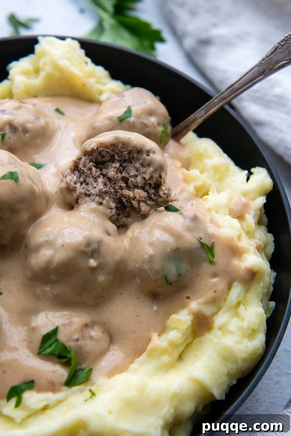 Effortless Oven Baked Gluten-Free Swedish Meatballs 2 Swedish meatball broke open in a bowl of mashed potatoes, showcasing its juicy interior.