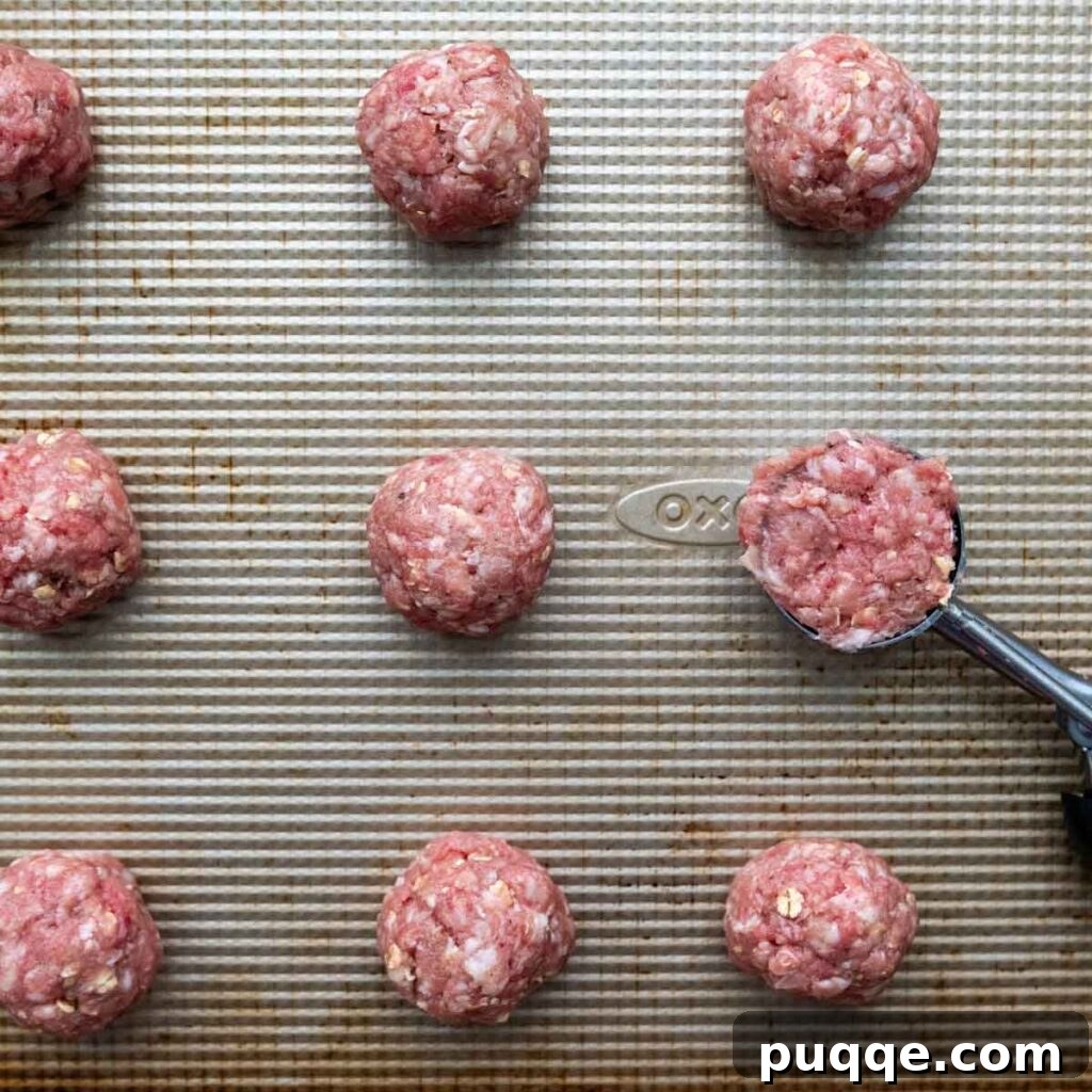 Effortless Oven Baked Gluten-Free Swedish Meatballs 4 Unbaked gluten-free Swedish meatballs arranged neatly on a baking sheet.