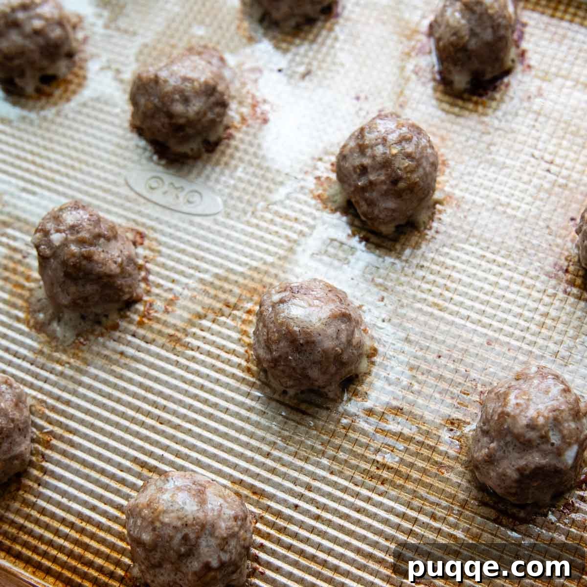 Effortless Oven Baked Gluten-Free Swedish Meatballs 5 Baked and browned gluten-free meatballs on a baking sheet, fresh from the oven.