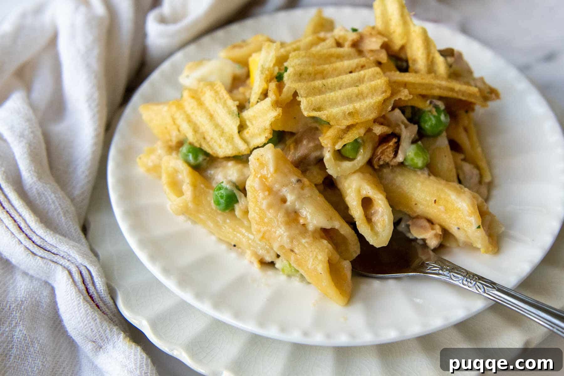 Wholesome Gluten-Free Tuna Noodle Casserole 7 close up of casserole serving on a white plate with a fork going into it