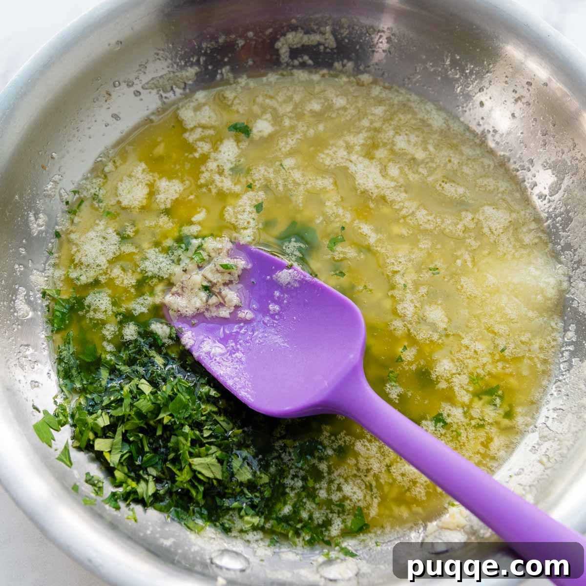 Melted butter and olive oil simmering in a skillet with minced garlic and fresh parsley, fragrant and ready for the bread.