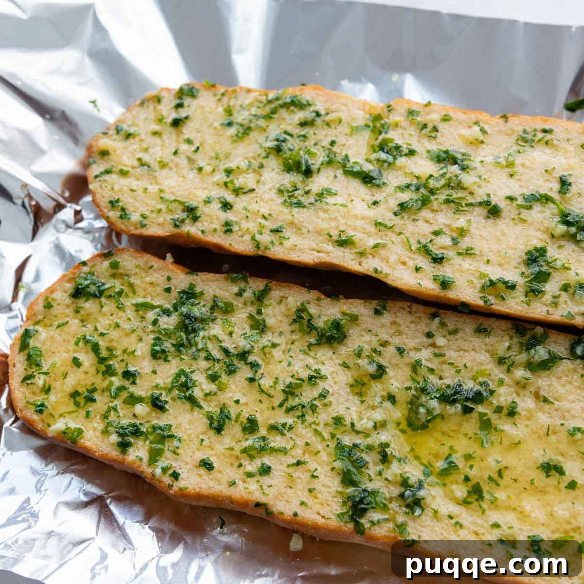 Garlic butter mixture being generously brushed over the cut sides of a split gluten-free bread loaf.